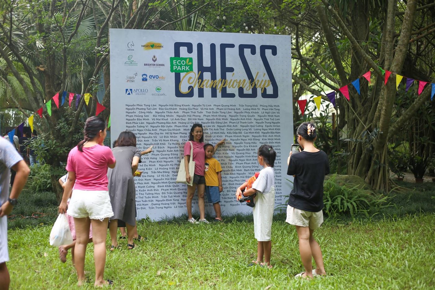 Phụ huynh và kỳ thủ bên bảng tên Ecopark Chess Championship